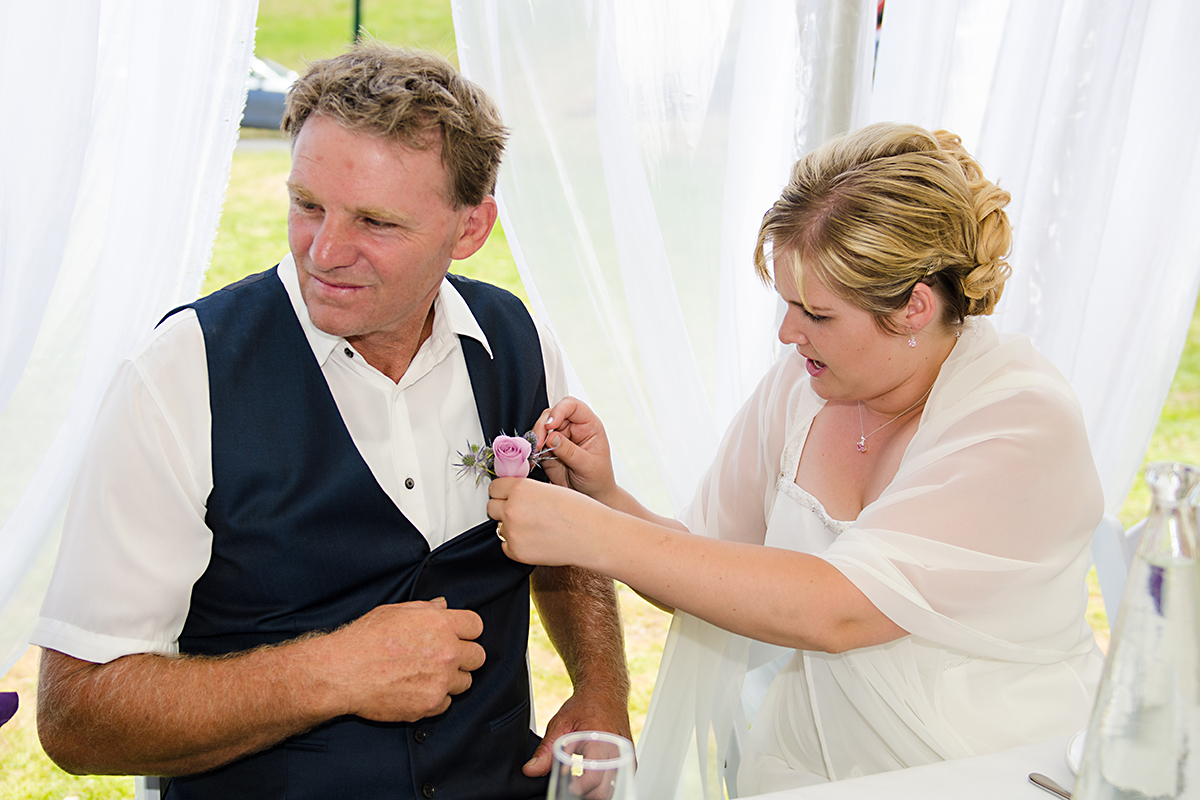 bride is helping groom with the flower